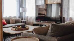 A cozy living room with a sofa, a coffee table, and a television.