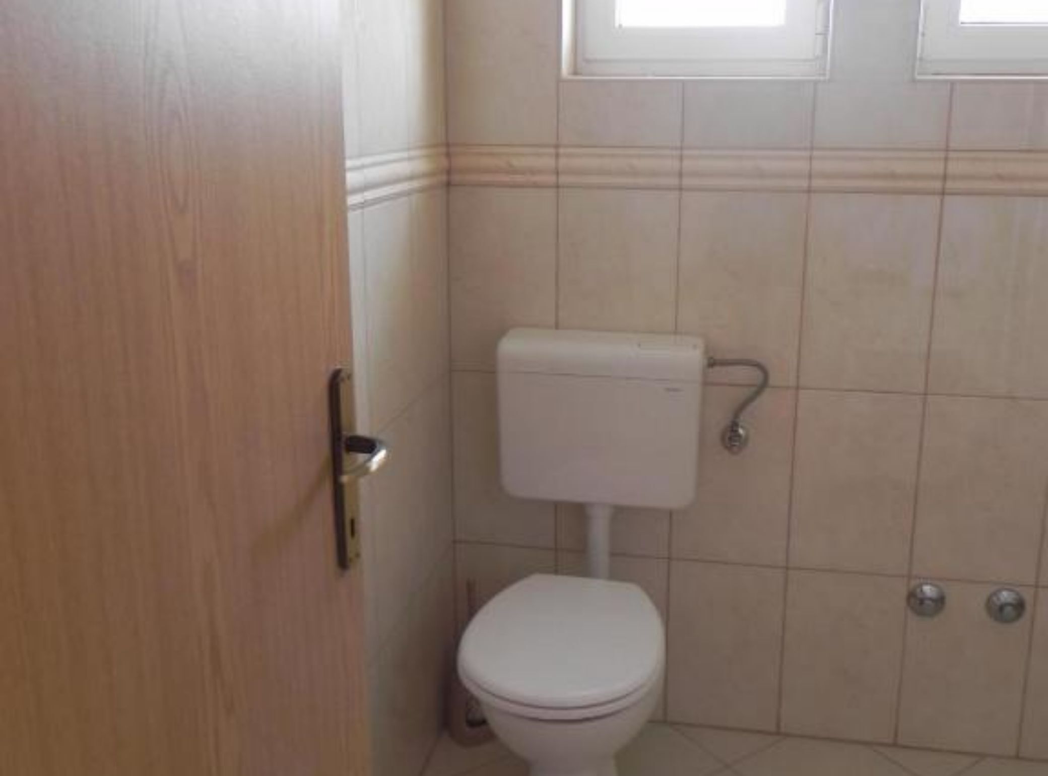A small, clean bathroom with a toilet, a sink, and a door.