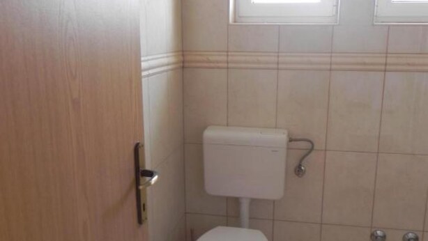 A small, clean bathroom with a toilet, a sink, and a door. - Apartments Trogrlić (Hvar)