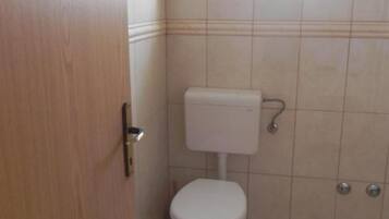 A small, clean bathroom with a toilet, a sink, and a door.