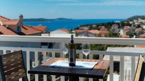 En balkon med et bord dækket til to, med udsigt over en kystby og havet.