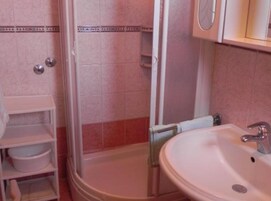 Un baño con ducha, lavabo y estanterías.