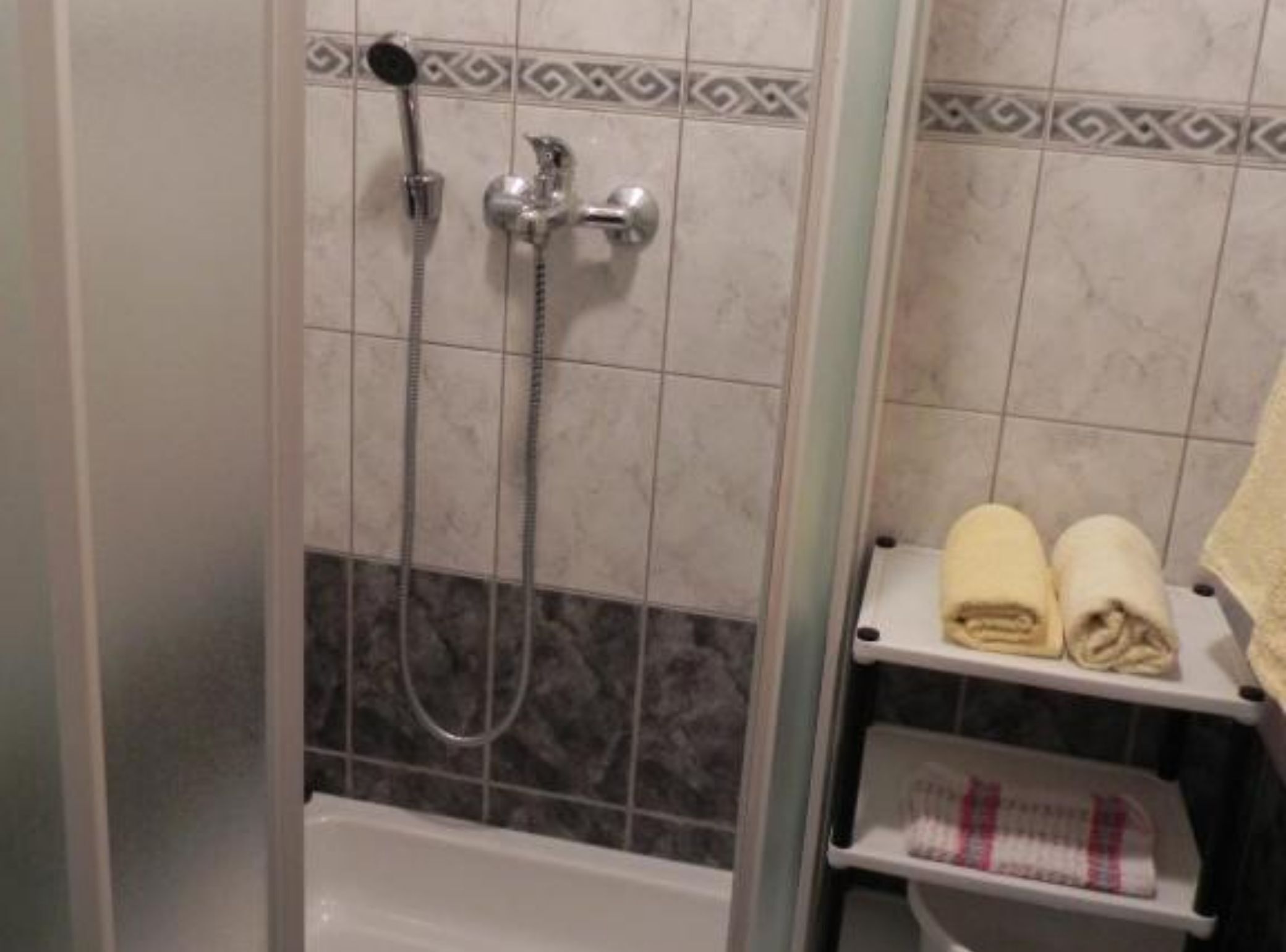 Un baño con ducha, bañera y un perchero con toallas.