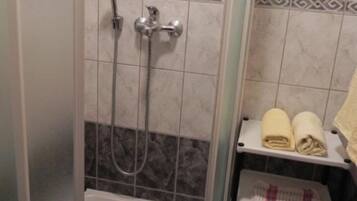 Un baño con ducha, bañera y un perchero con toallas.