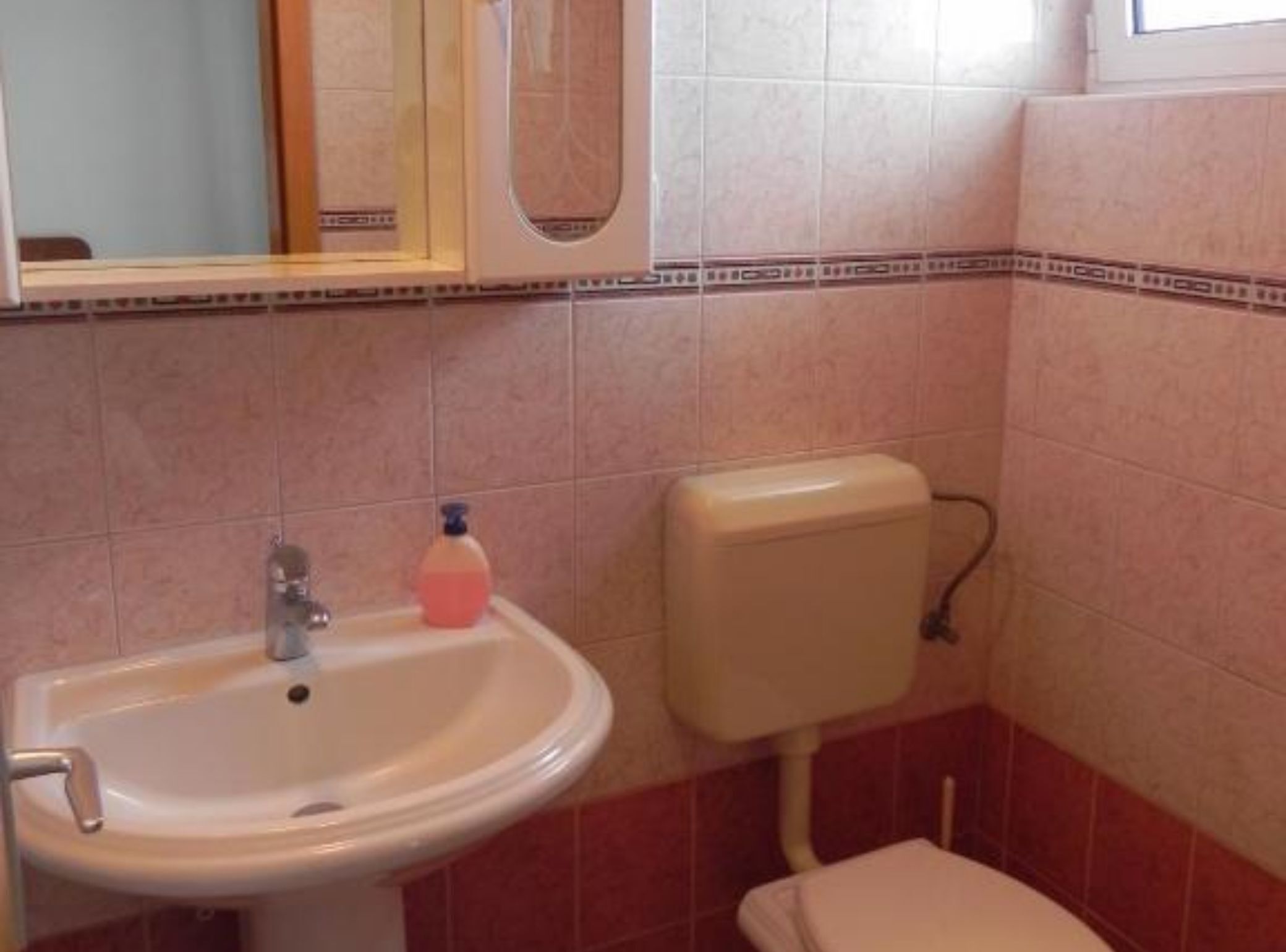 Une salle de bain avec un lavabo, des toilettes et un miroir.
