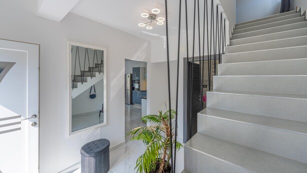 Una escalera moderna con diseño minimalista, una planta en maceta y una lámpara contemporánea.