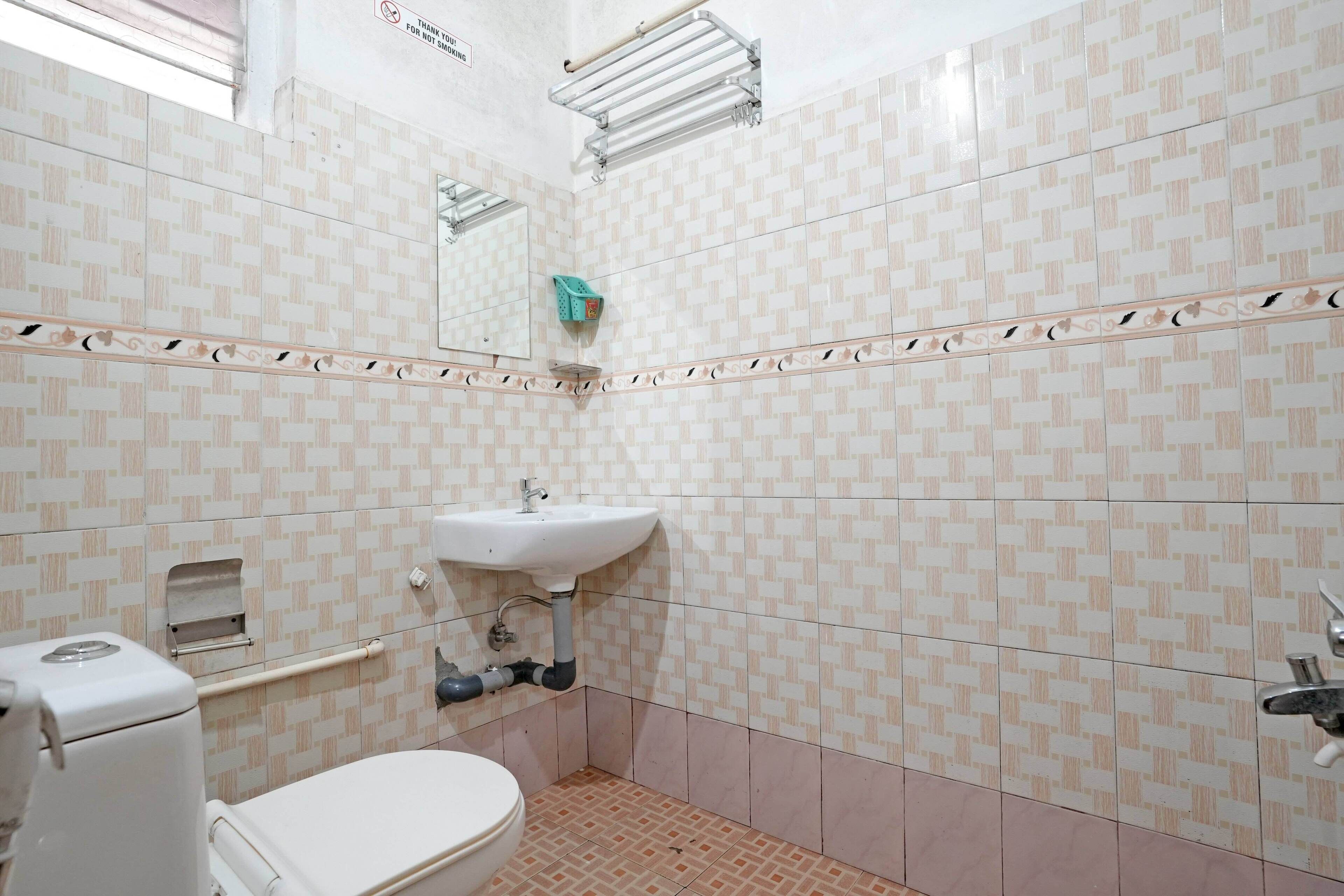 Une salle de bain avec des carreaux décorés, des toilettes, un lavabo et un porte-serviettes.