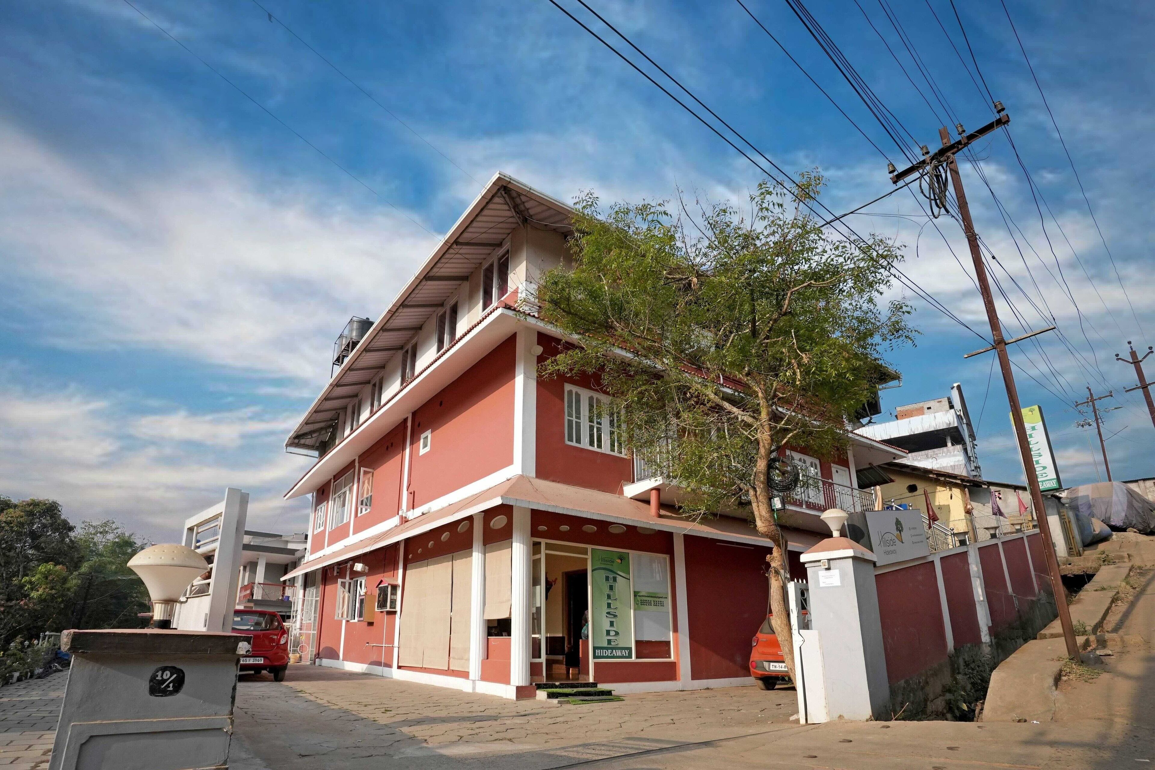 A two-story building with a red facade, a balcony, and a visible entrance.