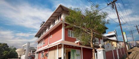 A two-story building with a red facade, a balcony, and a visible entrance.