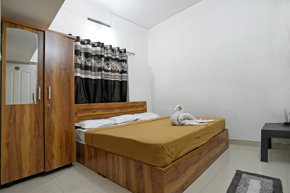 A bedroom with a wooden bed, a wardrobe, a curtain, and a small table.