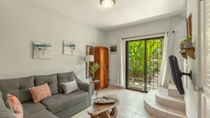 A living room with a grey sofa, a wooden coffee table, and a sliding glass door leading to a balcony. - Pura Armonia Condo with Outdoor Patio (Playas Del Coco)