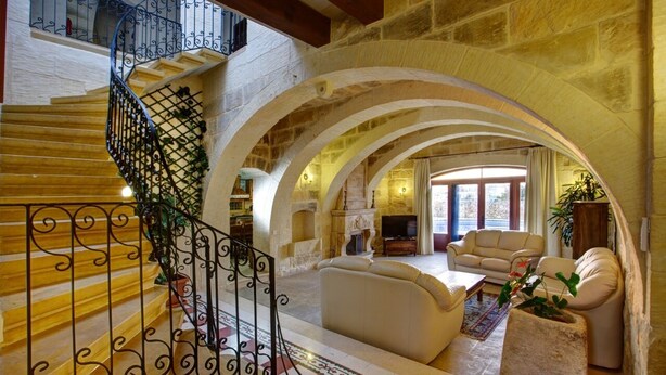 Amplia sala de estar con escaleras, arcos de piedra y chimenea.