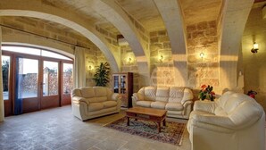 Amplia sala de estar con arcos de piedra, sofás de cuero y una mesa de centro de madera.