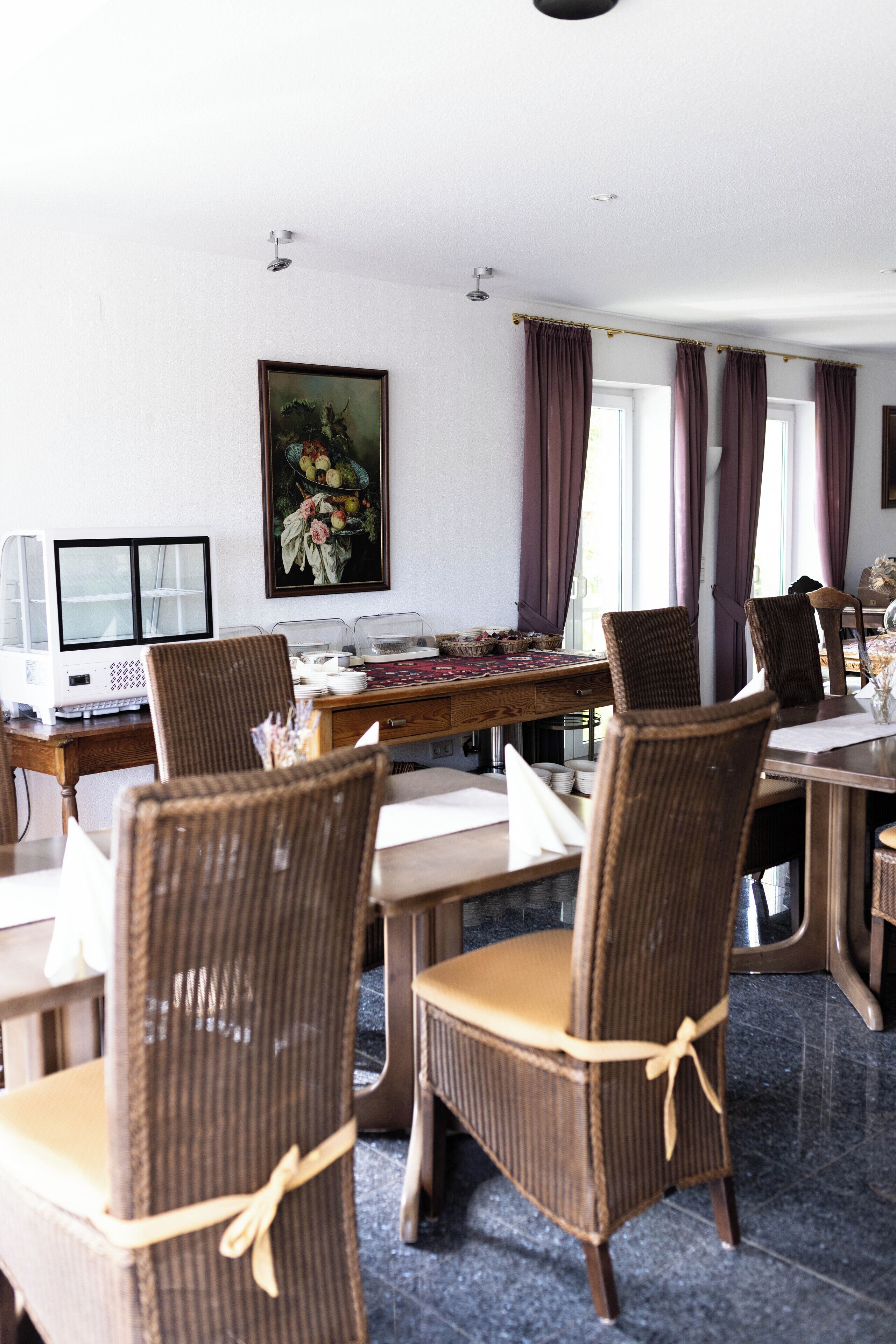 Un coin repas avec des chaises en osier, une table en bois et un tableau accroché au mur.