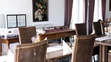 Un coin repas avec des chaises en osier, une table en bois et un tableau accroché au mur.