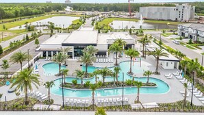 Un hotel con un amplio área de piscina, múltiples sillones de descanso y vista a un cuerpo de agua.