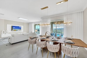 Un comedor moderno con una mesa de madera, sillas blancas tapizadas y detalles dorados.