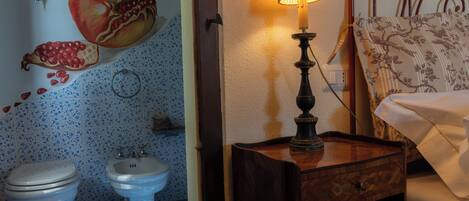 Casa de banho com sanita, bidé e um mural decorativo de romãs na parede.