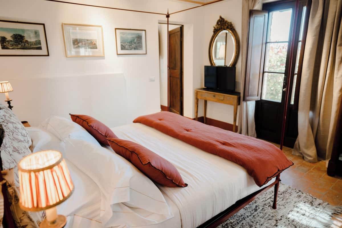 A bedroom with a bed, a bedside table, a lamp, and a mirror.