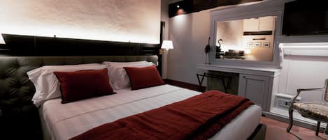 A bedroom with a large bed, a red blanket, and a wooden headboard.