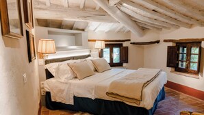 Une chambre à coucher avec un lit, des lampes de chevet, une fenêtre et un plafond en bois rustique.