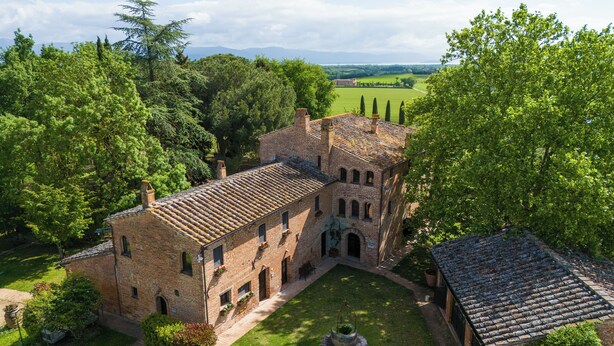 Un bâtiment historique doté d’une cour intérieure, entouré d’une végétation luxuriante et d’arbres.