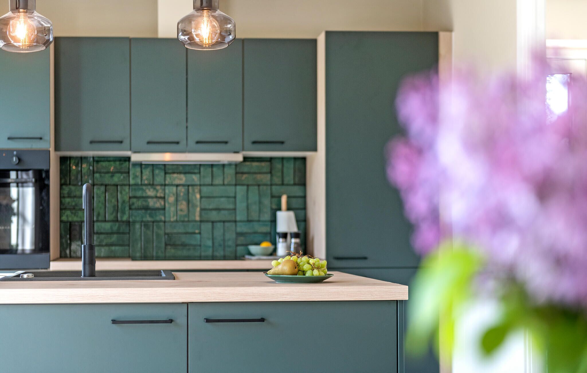 Une cuisine moderne avec des armoires de couleur turquoise, un plan de travail en bois et un évier apparent.