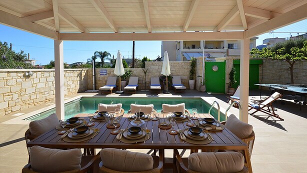 An outdoor dining area with a pool, covered seating, and a stone wall. - Villa Ithaca.  Country side villa close to all worth visiting sights in Chania.  (CHANIA)