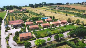An aerial view of a residential area with terraced houses, a swimming pool, and fields.