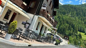 A hotel with a balcony, outdoor seating, and a mountain backdrop. - Jägerheim (Ernen)