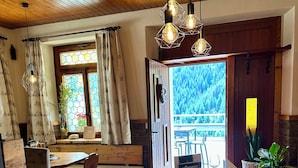 A wooden dining area with a large table, chairs, and hanging light fixtures. - Jägerheim (Ernen)