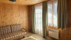 A wooden-paneled room with a sofa and a bed. - Jägerheim (Ernen)