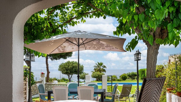 An outdoor patio with a round table, chairs, and a large umbrella. - Quiet 4-bedroom house near Munts beach, air-conditioned, shared pool (Torredembarra)
