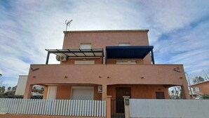 A two-story building with a flat roof, a covered entrance, and a gated driveway. - Ground Floor Apartment with Air Con, Terrace, and Shared BBQ - Sleeps 6 (Marseillan-Plage)