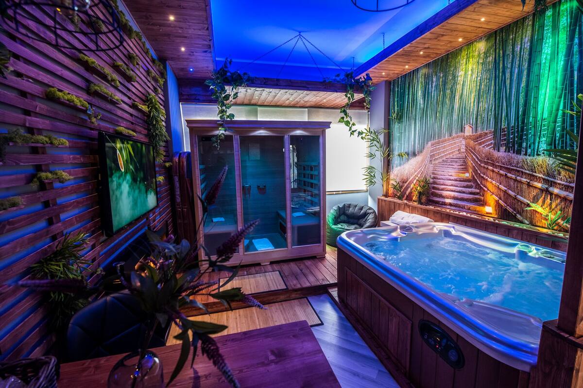 Un moderno espacio de spa con un jacuzzi, suelo de madera y una zona de estar con paredes de cristal.