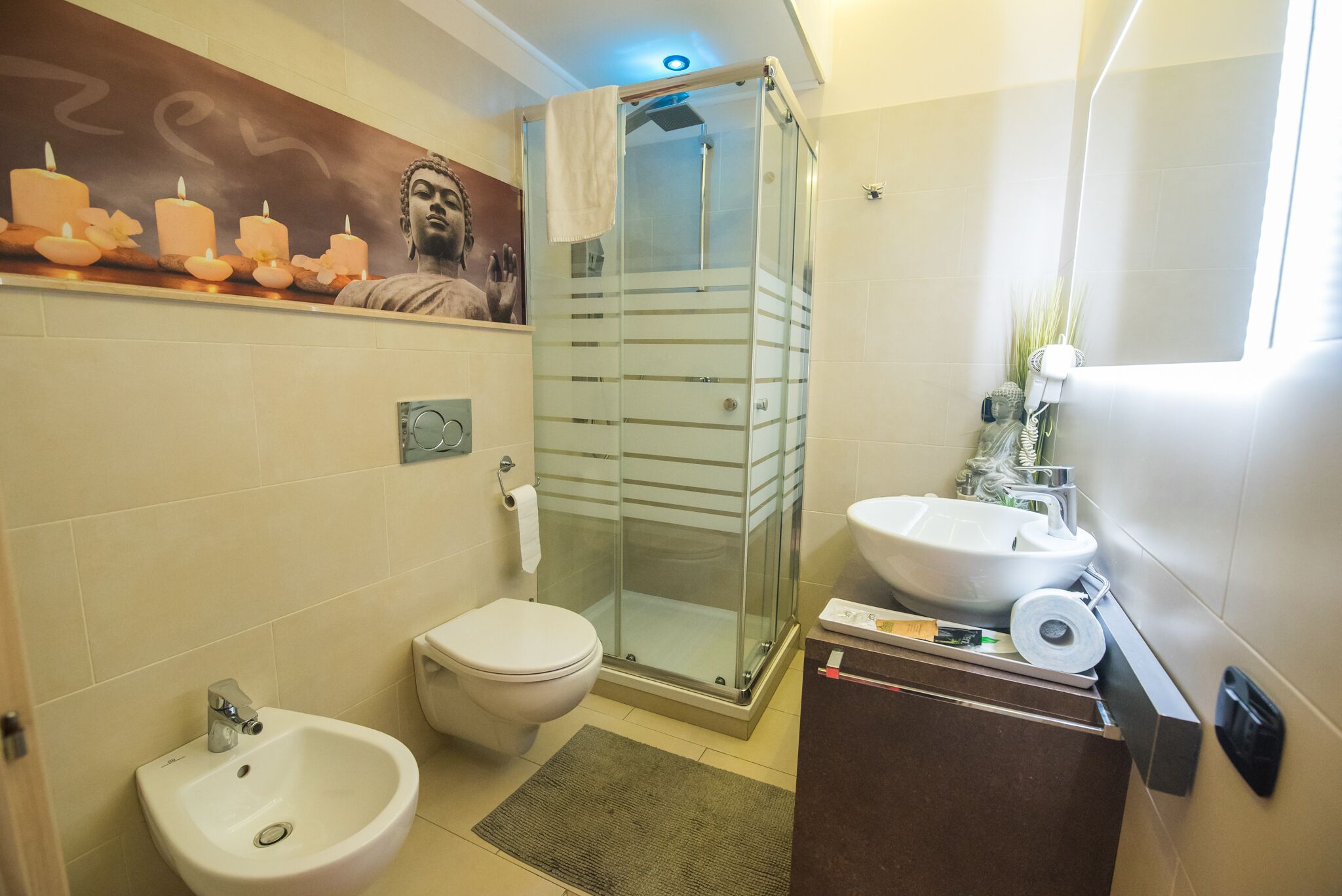 A modern bathroom with a glass-enclosed shower, a bidet, a toilet, and a sink.