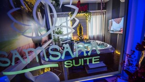 Una suite de hotel moderna con una estatua de Buda, un televisor y un cartel que dice 'SANTISARA SUITE'.