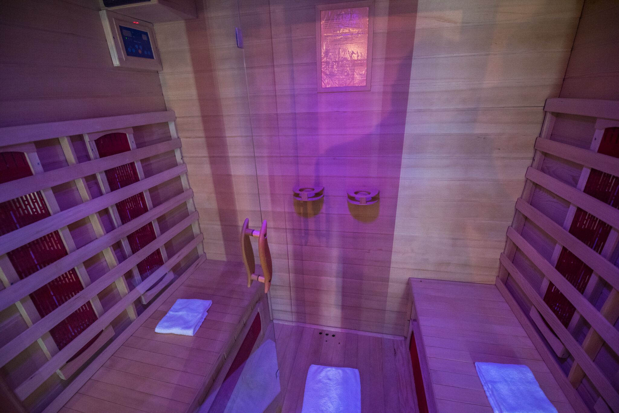 A sauna room with wooden benches and benches, a wooden wall, and a small window.