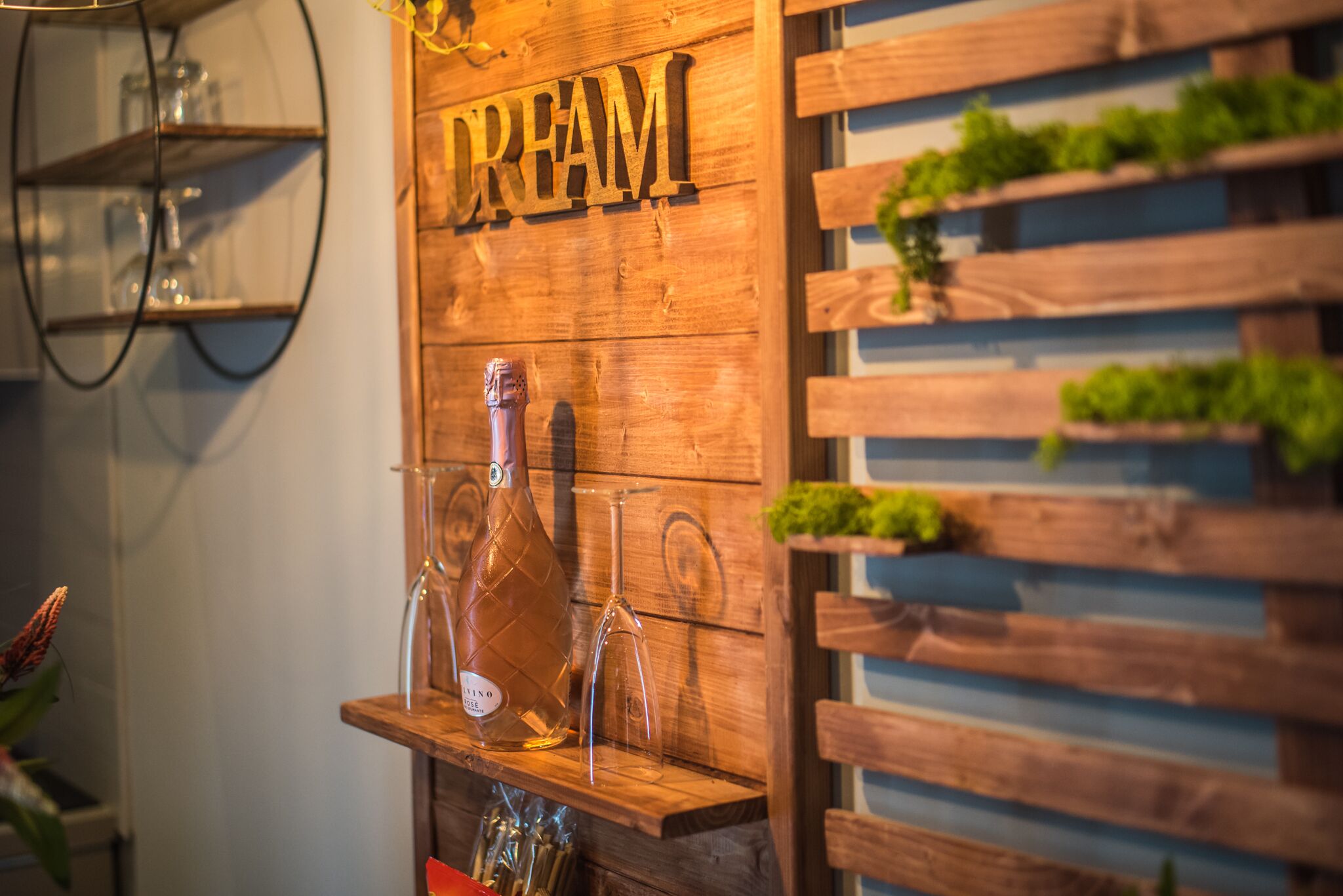 A wooden shelf with a bottle and glasses, and a sign that reads "DREAM".