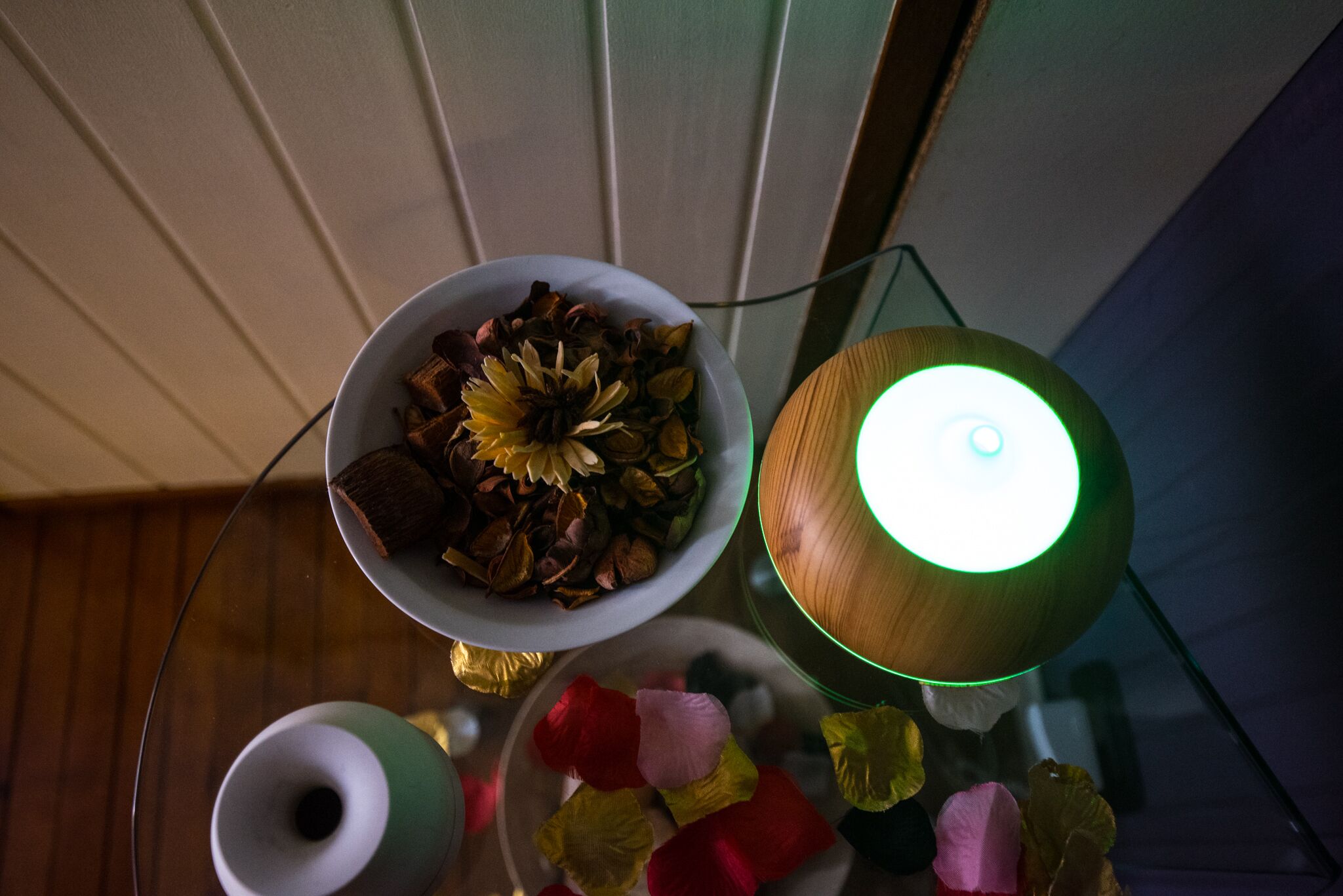 Une table avec un bol rempli de fleurs séchées, une lampe en bois et une tasse.
