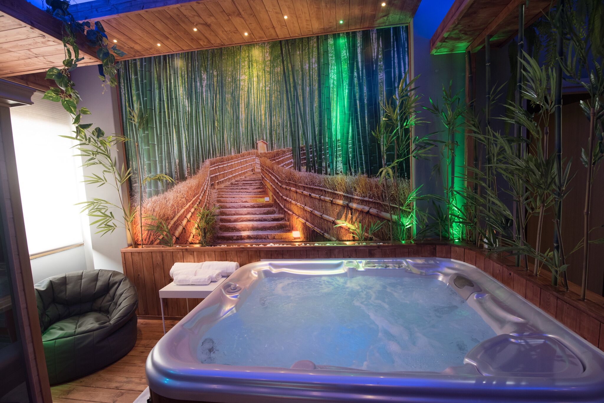 A spa area with a hot tub, bamboo wall, and a staircase.