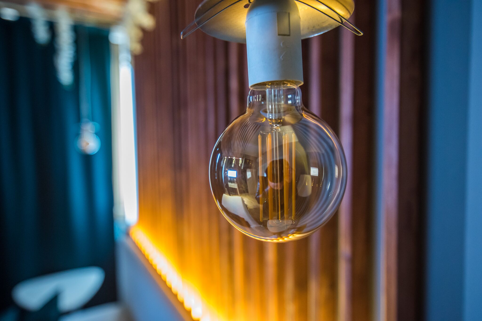 Una lampada a sospensione con paralume bianco e base metallica, appesa al soffitto.