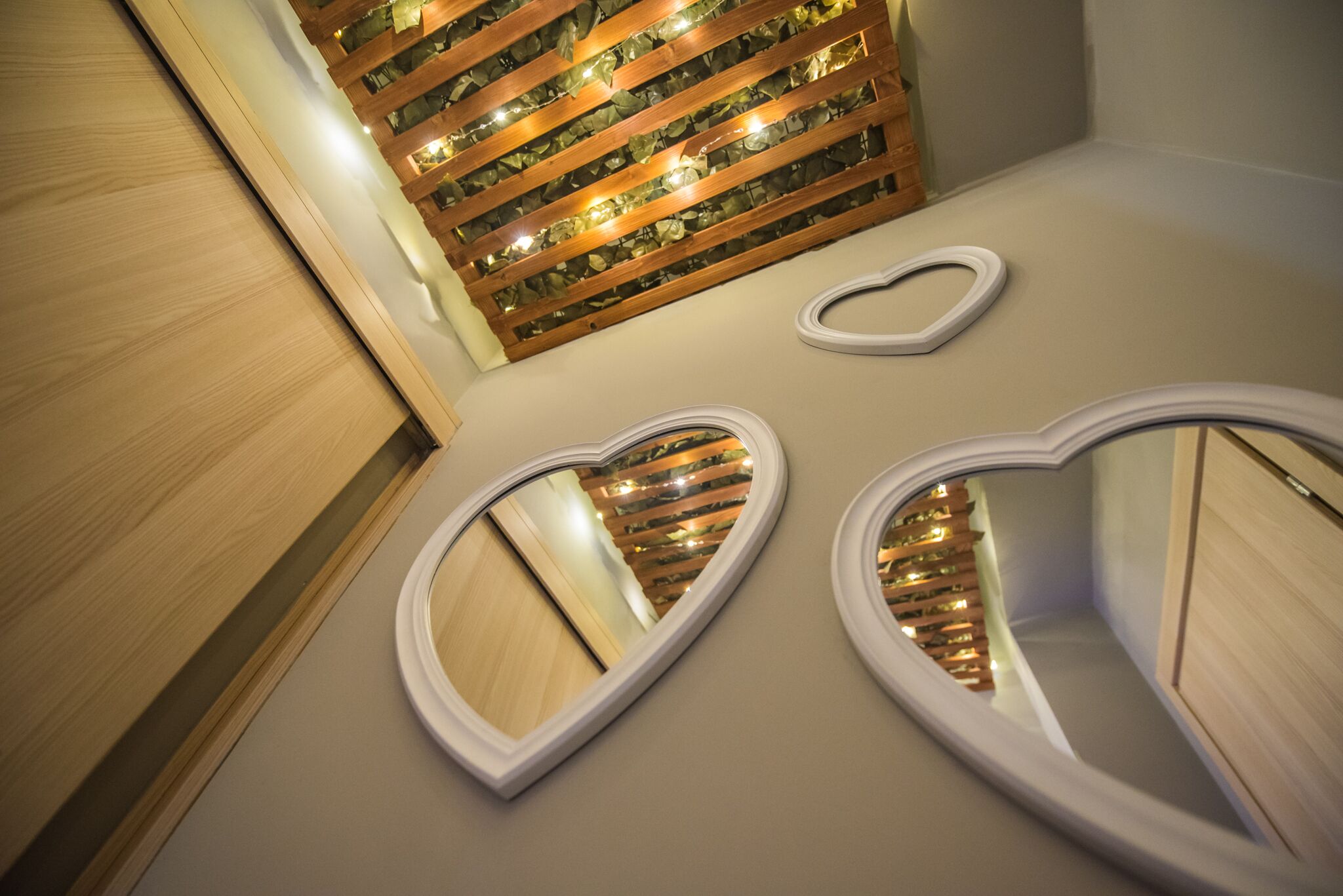 A bathroom with wooden paneling, a mirror, and a heart-shaped mirror on the wall.