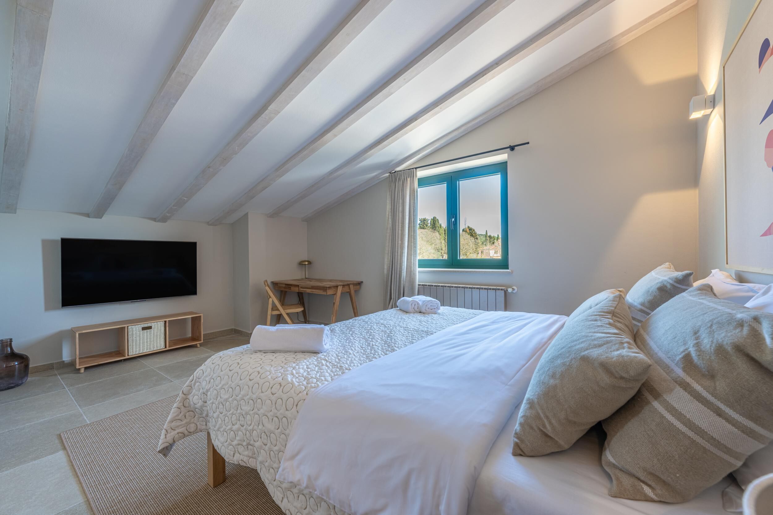 Ein Schlafzimmer mit einem Bett, einem Fernseher, einem kleinen Tisch und einem Fenster mit Blick.