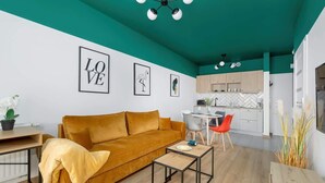 Uma sala de estar moderna com um sofá amarelo-mostarda, uma mesa de centro e um espaço de refeições com cadeiras.