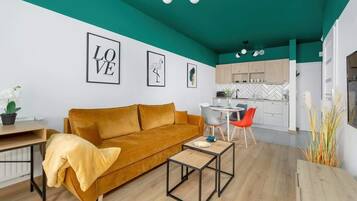 A modern living room with a mustard sofa, a coffee table, and a dining area with chairs.