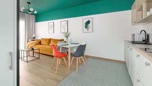Uma sala de estar moderna com teto verde-água, sofá amarelo, mesa de jantar com cadeiras e uma área de cozinha com armários e pia.