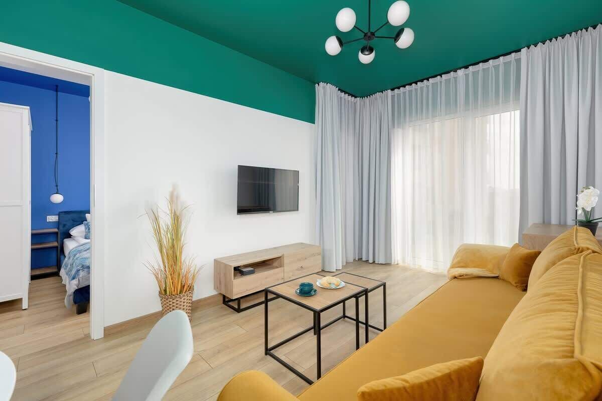 Ein modernes Wohnzimmer mit einer türkisfarbenen Akzentwand, einem Sofa, einem Couchtisch und einem Fernseher.