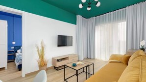 Uma sala de estar moderna com uma parede em tom de verde-água, um sofá, uma mesa de centro e uma televisão.