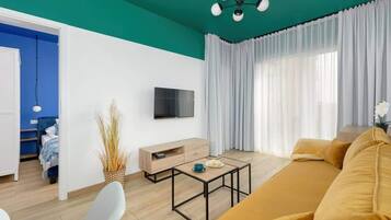 Ein modernes Wohnzimmer mit einer türkisfarbenen Akzentwand, einem Sofa, einem Couchtisch und einem Fernseher.